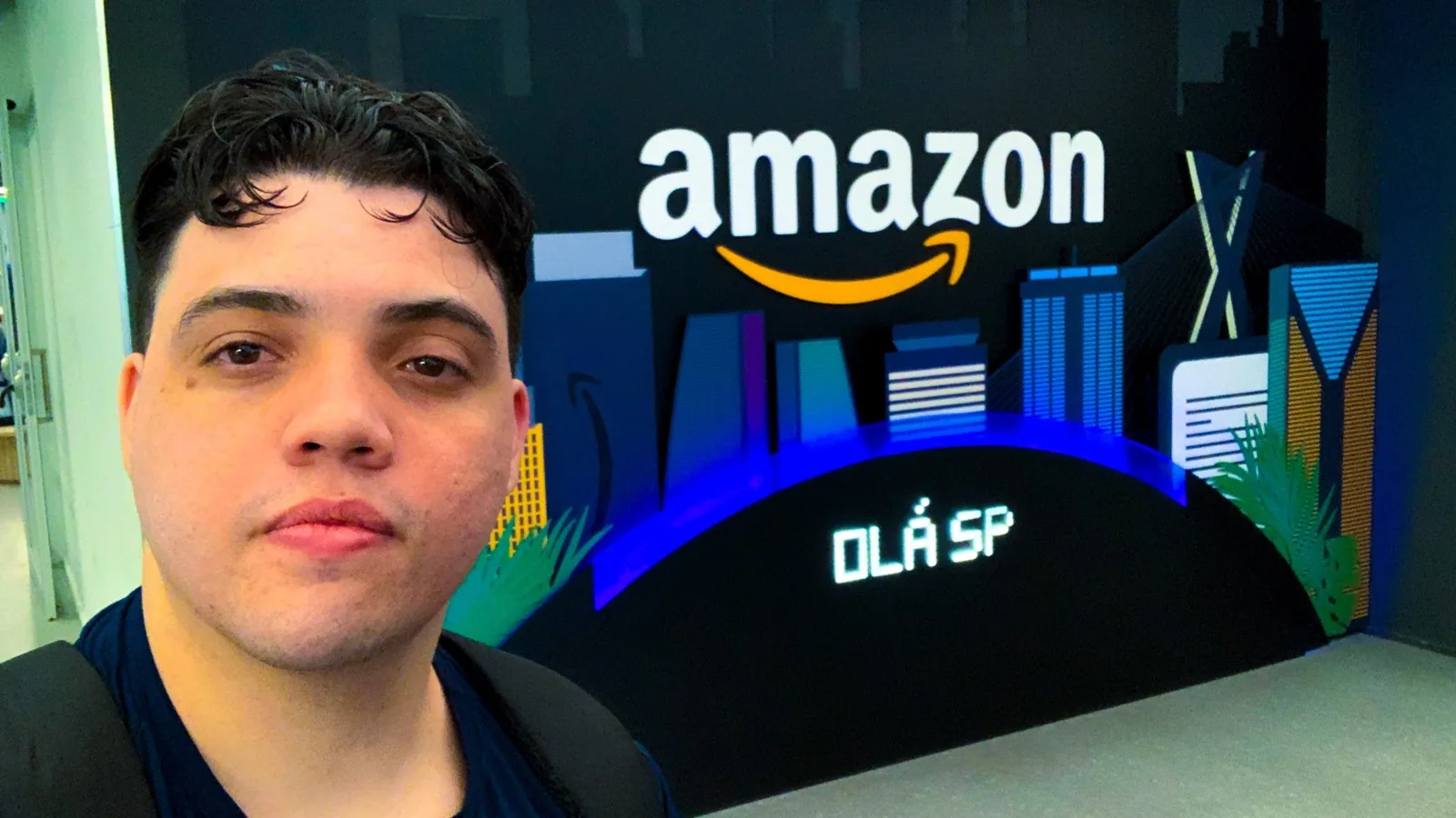 Cleidson Oliveira em selfie demonstrando o logo da Amazon e a mensagem 'Olá SP', no dia de um evento sobre GenAI aplicada em ambientes regulamentados.